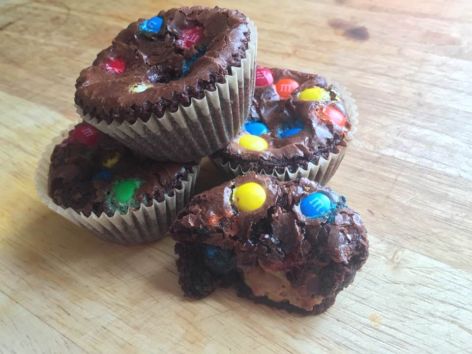 A pile of three peanut butter brownie bites with m&m's and a half of a fourth one.