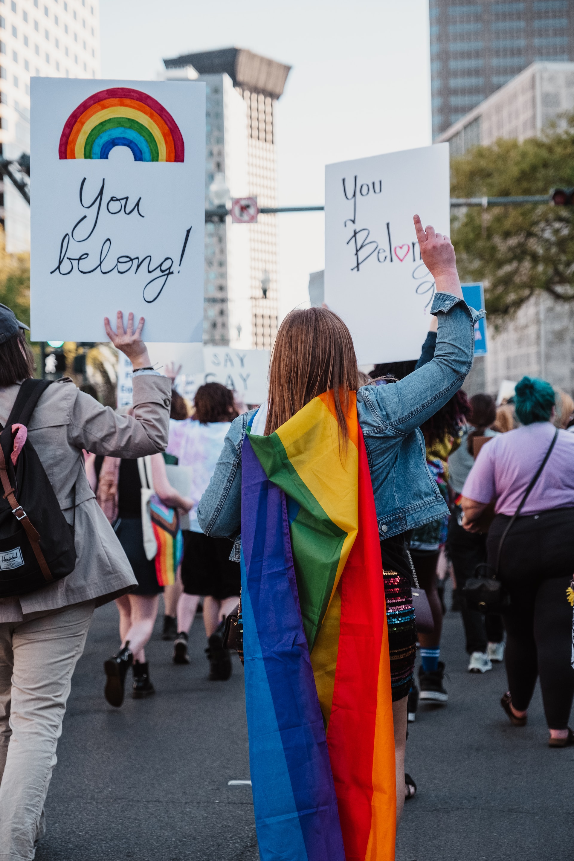 A photo of Pride Protestors holding signs that read, You Belong!